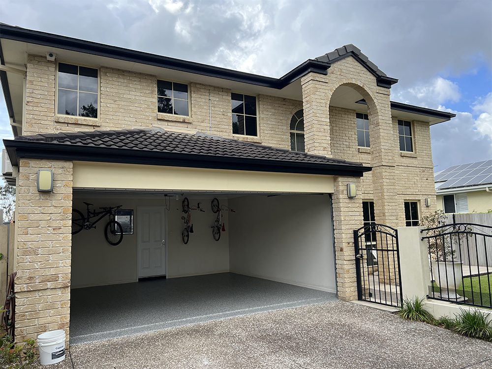 A wide-angle photo of a home garage with the door open showing the new Resin Vinyl epoxy flake floor.