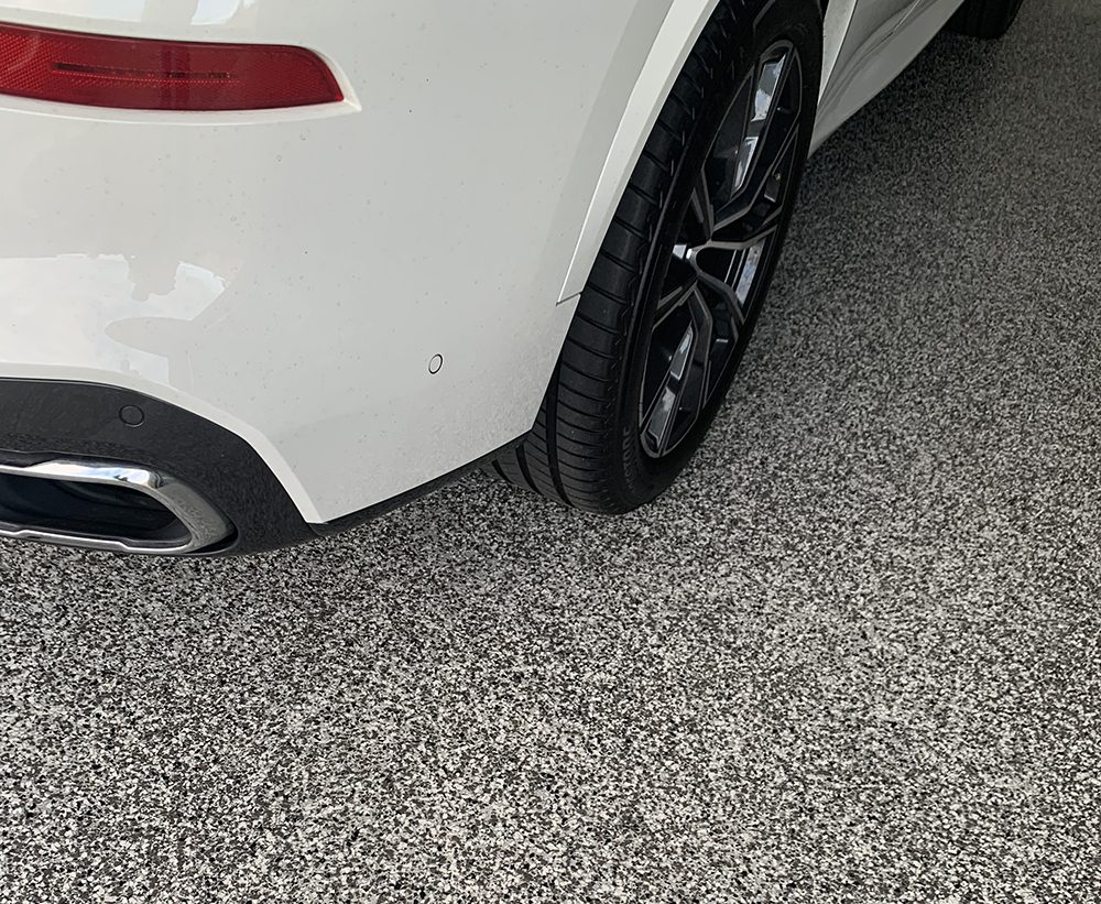 A close up of a car tyre parked on new Resin Vinyl epoxy flake floor.