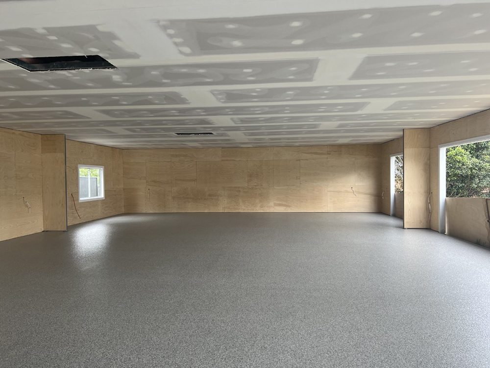 A large, empty garage that's still being furnished inside with a new Resin Vinyl epoxy flake floor.